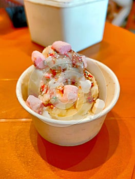 A small bowl of ice with a pink and white topping