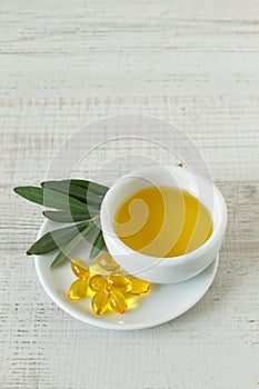 Small bowl with olive oil and natural pills