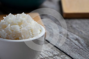 small bowl with rice in the foreground and some kitchen utensils photo