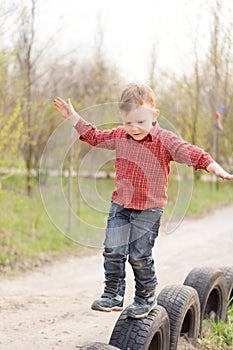 Small boy balancing on old tyres