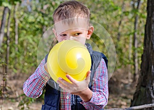 Small boy blowing up a colorful yellow balloon photo