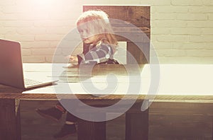 Small boy and business kid with laptop on wooden chair