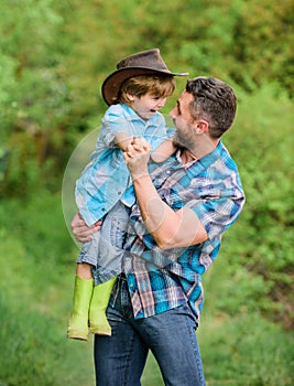 Small boy child help father in farming. father and son in cowboy hat on ranch. kid in rubber boots. happy man dad in