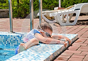 Small boy clambering out of a swimming pool