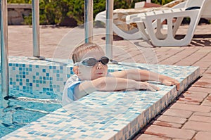 Small boy clambering out of a swimming pool