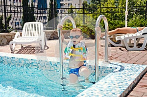 Small boy clambering out of a swimming pool