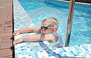 Small boy clambering out swimming pool