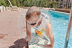 Small boy clambering out of a swimming pool