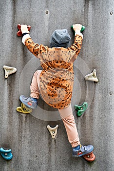 Small boy climbing a rock wall at playground