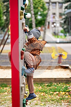 Small boy climbing a rock wall at playground