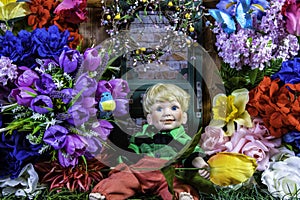 Small boy doll surrounded by colorful flowers