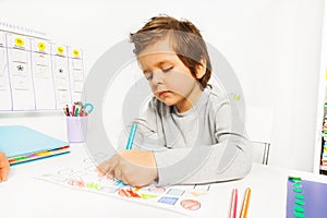 Small boy draws with pencil on the paper sitting