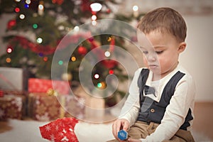 Small boy enjoying plenty of gifts under garnished christmas tree