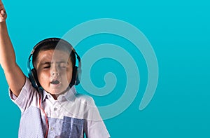 Small boy with expressive face listening to music on headphones dancing and singing authentic unposed image with copy space for