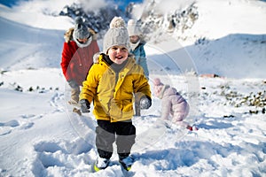 Small boy with family in winter nature, walking in the snow.