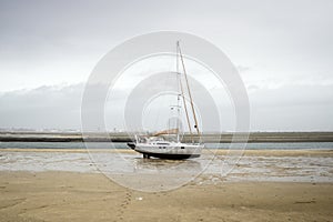 A small boy heading sailing boat on the sand during low tide, Portugal