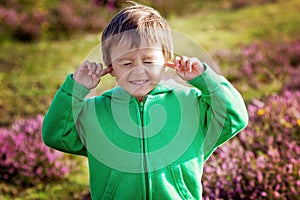 Small boy holds his hands over ears not to hear