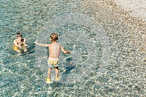 Small boy jumps from stone pier to sea touching water