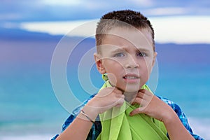 Small boy, kid at the beach looking at you camera pensive