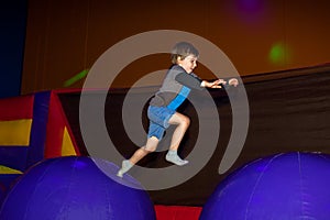 Small Boy Leaps from One Inflatable Obstacle to Another in an In