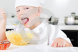 Small boy learning to cook checking his mixture