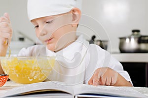 Small boy learning to cook checking his mixture