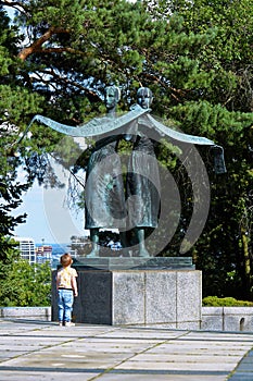 small boy looks on big statue