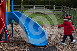 A small boy playing on a slide at the park