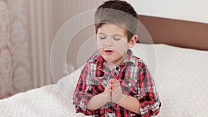 Small boy praying, kid saying prayer before going to bed, strong belief in heart, boy praying to god