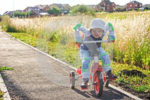 Small boy rides a tricycle on a track in the suburb