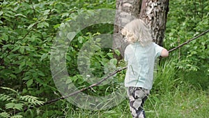 Small boy runs along green forest on summer time outdoor.