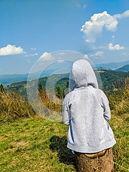 Small boy sitting on the carpathian mountains background
