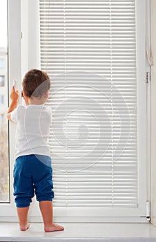 Small boy standing on window-sill