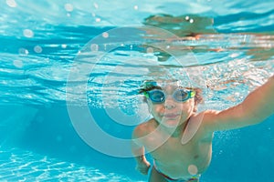 Small boy swimming wearing goggles under water