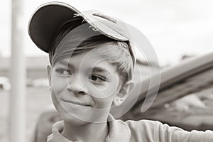 A small boy in a t-shirt and cap poses for the camera