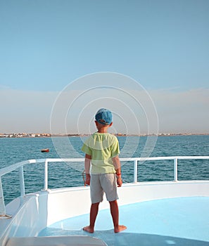 Small boy watches horizon on sailboat