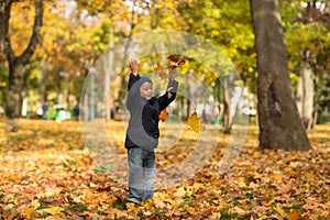 A small boy wearing jeans and a blue jacket joyfully throws ye