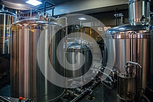 Small brewery. Industrial stainless steel pipes connected with vats and control valves
