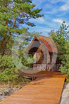 Small brick house under red tiled roof among dunes and pines in a national park public space. Russia, Kaliningrad, Zelenogradsk