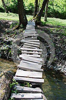 Small bridge made of wood between the banks of a small river. Rudimentary construction
