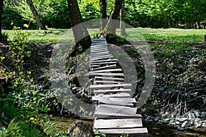 Small bridge made of wood between the banks of a small river. Rudimentary construction