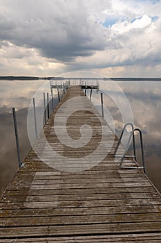 A small bridge over the lake. Reflection of clouds on the lake's surface