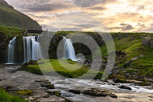 Small bridge over a waterfall and cloudy sky at sunset