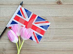 Small British flag with pink tulips on a wood background