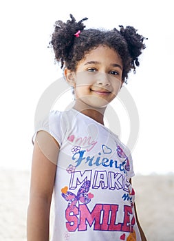 Small brown girl African American appearance with curly hair laughing out loud and looking at the camera