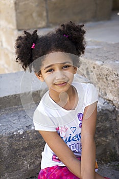 Small brown girl African American appearance with curly hair laughing out loud and looking at the camera