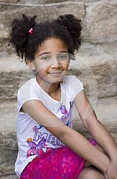 Small brown girl African American appearance with curly hair laughing out loud and looking at the camera
