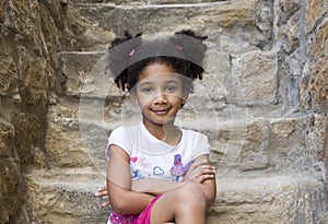 Small brown girl African American appearance with curly hair laughing out loud and looking at the camera