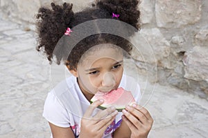 Small brown girl African American appearance eating watermelon