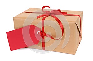 Small brown paper package or gift tied with red ribbon and gift tag isolated on white background